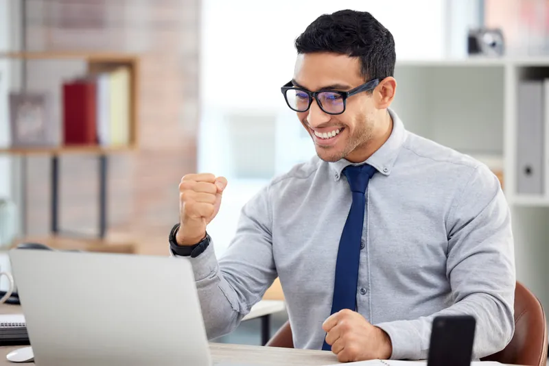 Man smiling and fist-pumping at his laptop after seeing his new internet speed and pricing offer